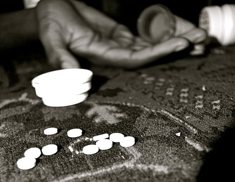 An image of a few pills strewn across from a hand to show abuse of drugs