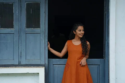 Darshana Rajendran is seen donning an tangerine dress in the image.