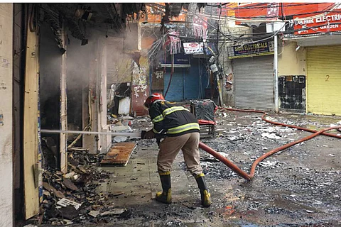 A fire official dousing flames at the Bhagirath Palace market in Delhi's Chandni Chowk