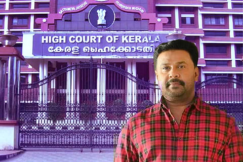 Actor Dileep in a red and black checked shirt against the backdrop of Kerala High Court
