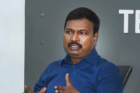 Dr G Srinivas Rao in a blue shirt addressing the media