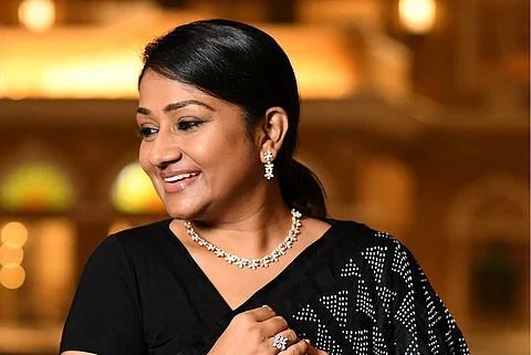Dolly Jain, professional sari and dupatta draper, smiling looking to her right in a black saree
