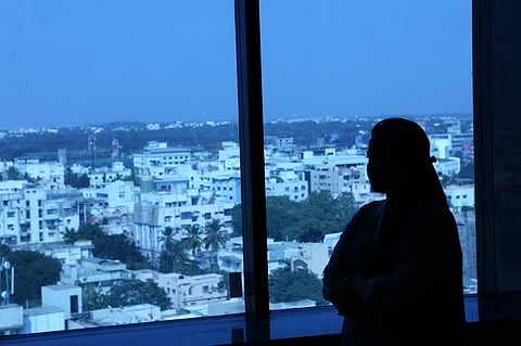 Silhouette of a woman with long hair looking out of the window