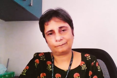 Dr Gangandeep Kang sits on a chair with a cupboard over a head