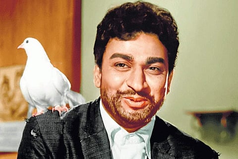 Dr Rajkumar is seen wearing a black coat and is seen along with a white dove.