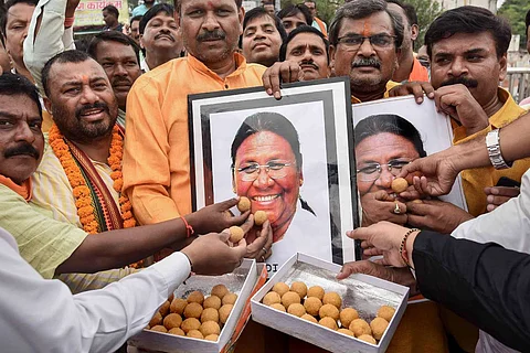 People feeding sweets to a photo of president-elect Draupadi Murmu