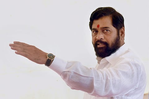File Image of Eknath Shinde wearing white shirt and holding up his hand
