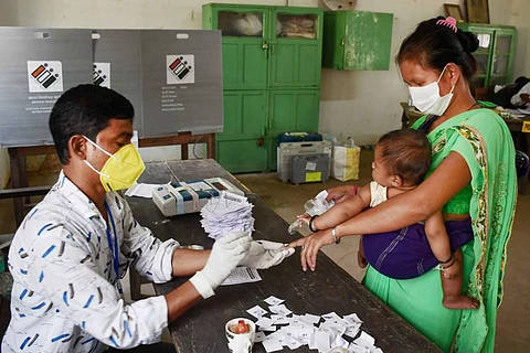 A polling official puts indelible ink on a woman voter as her baby sits on her hip