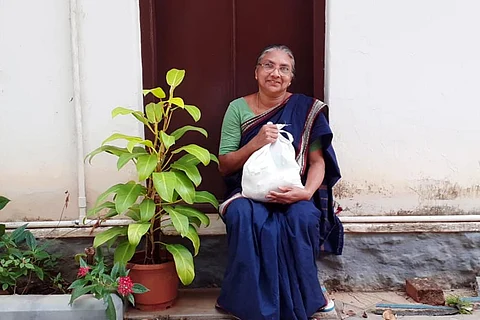A beneficiary posing for a photograph holding the Kerala government's free food kit