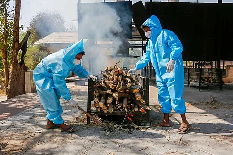 Frontline workers in personal protective equipment (PPE) arrange funeral pyre for Covid19 victim at a crematorium in Ahmedabad