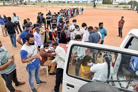 A health worker administers COVID vaccine to a beneficiary as others wait in a queue during a mobile vaccination drive by GHMC at Risala Bazar in Hyderabad