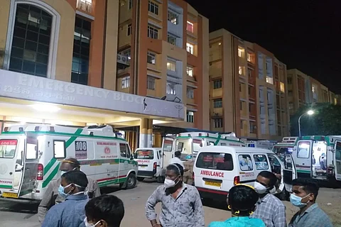 Several ambulances with patients wait at Gandhi Hospital for beds.