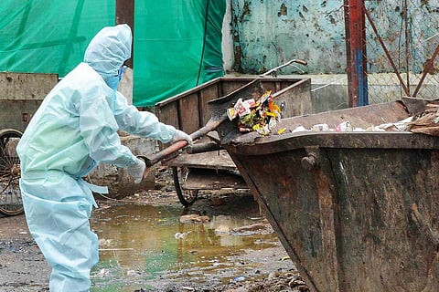 Sanitation worker in PPE disposing garbage