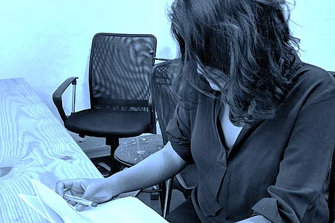 Representative image of a girl sitting at a table, looking down at a piece of paper