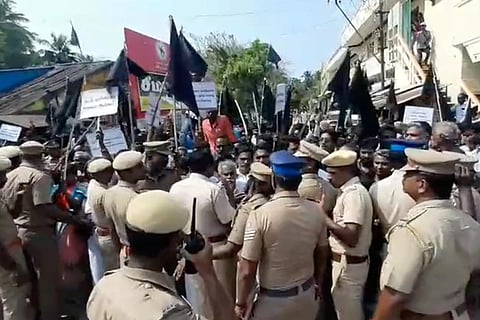 Protestors waving black flags barricaded by police