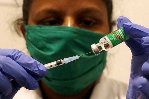 Health worker drawing vaccine using a syringe