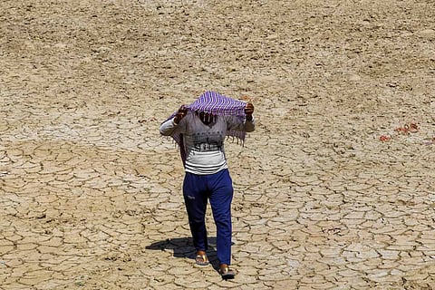 A man covers his head with a cloth in the sweltering heat