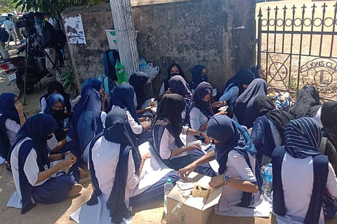 Girls in hijab sitting outside college gates in Kundapura