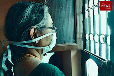 Lady wearing a mask staring out the window