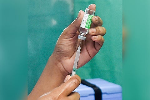 A person extracting Covid vaccine out of a vial