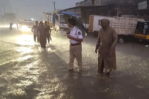 Traffic police personnel standing on waterlogged roads during Hyderabad rains