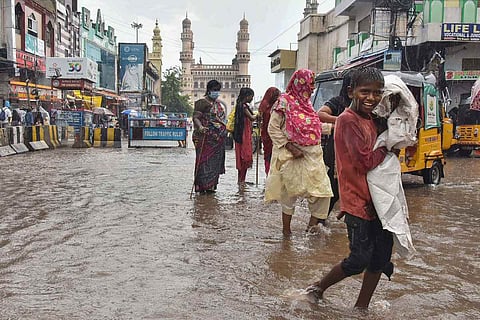 Commuters walk on a waterlogged street near the Charminar during rainfall