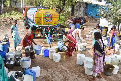 People fill their vessels with drinking water from a tanker in Hyderabad