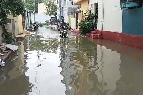 A man riding a motorcycle in a street overflowing with rain water
