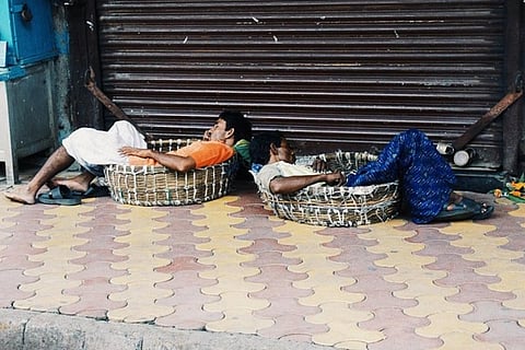 Two workers sleeping sitting in baskets outside a store shutter