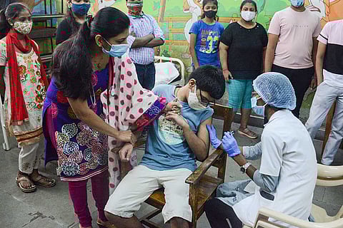 A healthworker administers a dose of COVID-19 vaccine to a teenager during a vaccination drive for 15-18 years age group, at a school