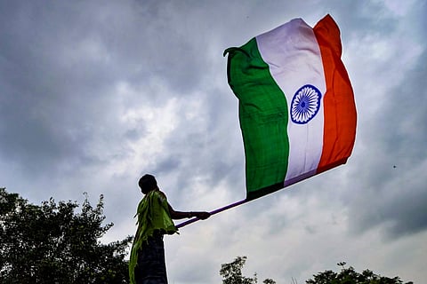 A person seen waving the Indian tricolour flag against the backdrop of the sky
