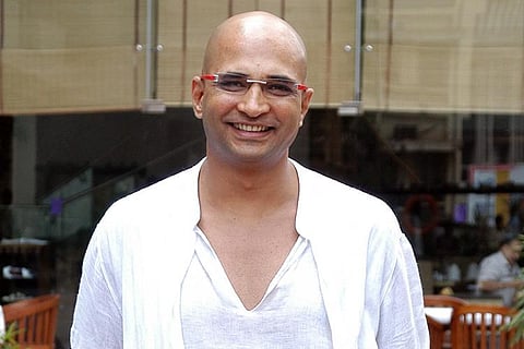 Indrajit Lankesh wearing a white shirt and smiling at the camera