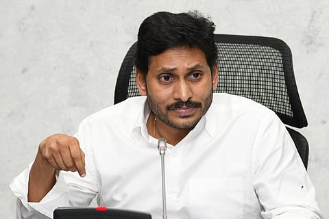 Andhra Pradesh Chief Minister Jagan Mohan Reddy wearing a white shirt, sitting at his desk in front of a mic