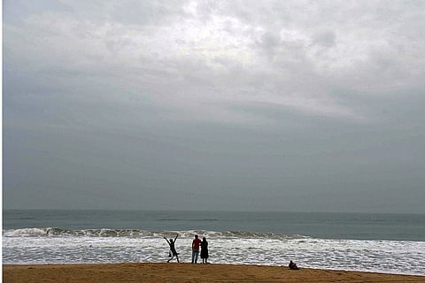 Three people at the beach with stormy skies overhead