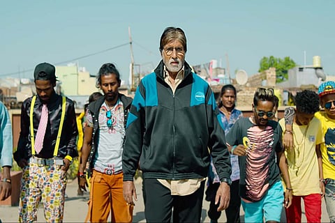A scene from Jhund featuring Amitabh Bachchan and other actors in the background