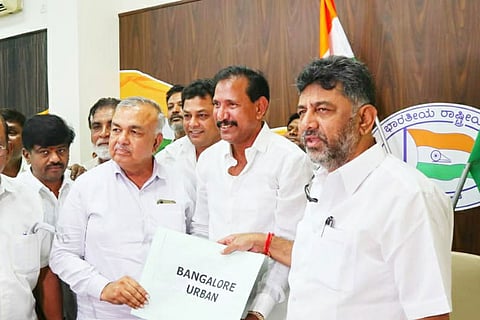 Yousuf Sharif holding a placard with 'Bangalore Urban' written on it, with Congress leader DK Shivakumar standing to his right