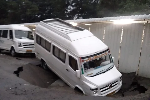 A van almost completely fallen into a giant hole after a road caved in at Chennai due to heavy rains
