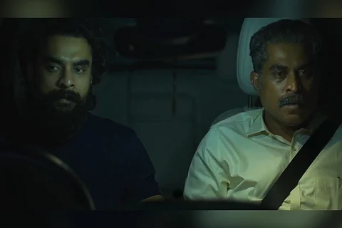 Tovino Thomas and Suraj Venjaramoodu sitting next to each other in the front seats of a car in Kaanekkaane