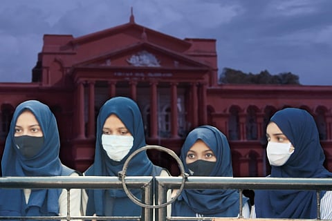 Four hijab-clad students in the foreground with the Karnataka High Court in the background