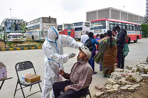 A health worker in PPE collects sample from a man for COVID-19 test