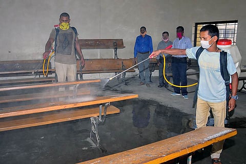 Two men disinfecting a classroom