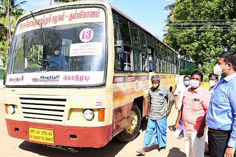 A new red and off-white Tamil Nadu public bus parked with people standing next to it