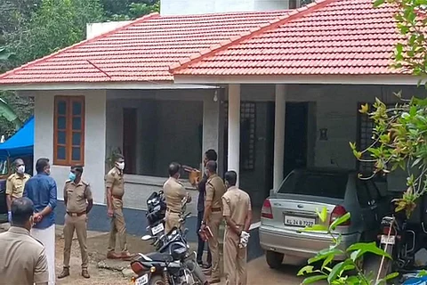 Several policemen in uniform and other bystanders standing outside the house where the crime took place
