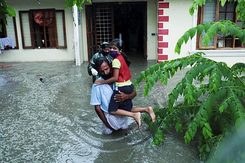 Man carrying daughter out of a flooded house in Kochi