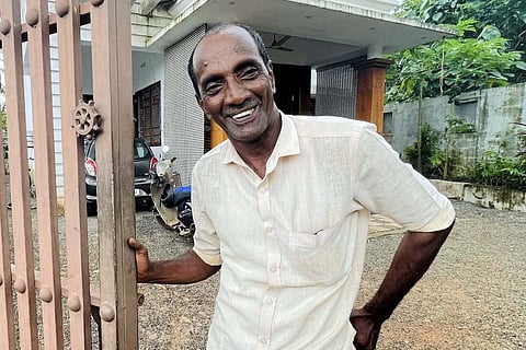 Mohammed Bava, in a white shirt, standing near the gate of his house