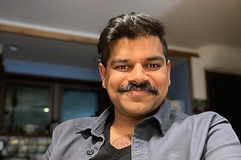 Kumar in a grey blazer and black shirt