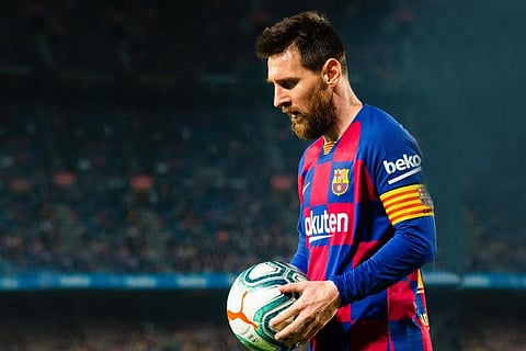 Lionel Messi with a ball in his hand before a set piece wearing the captain band and a Bercelona shirt