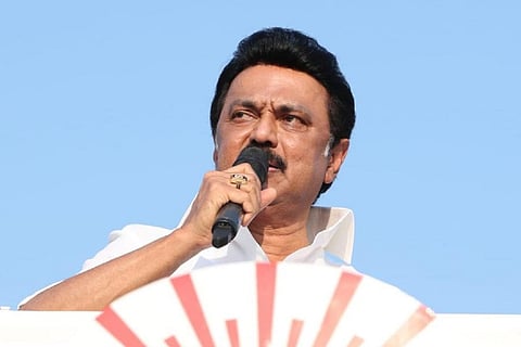 MK Stalin holding mike and talking against blue background