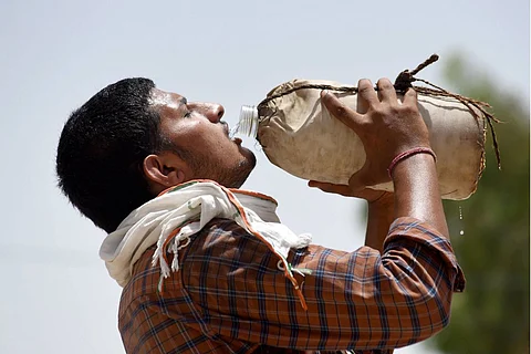 A labourer drinks water at a grain market on a hot summer day