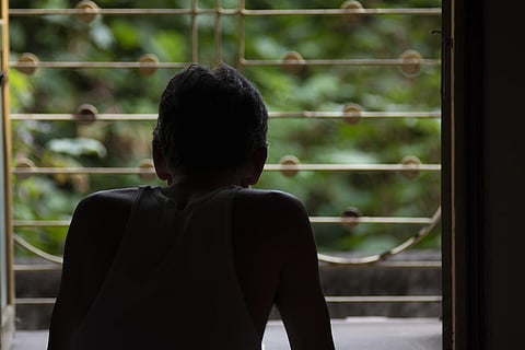 Silhoutte of a person standing facing a window